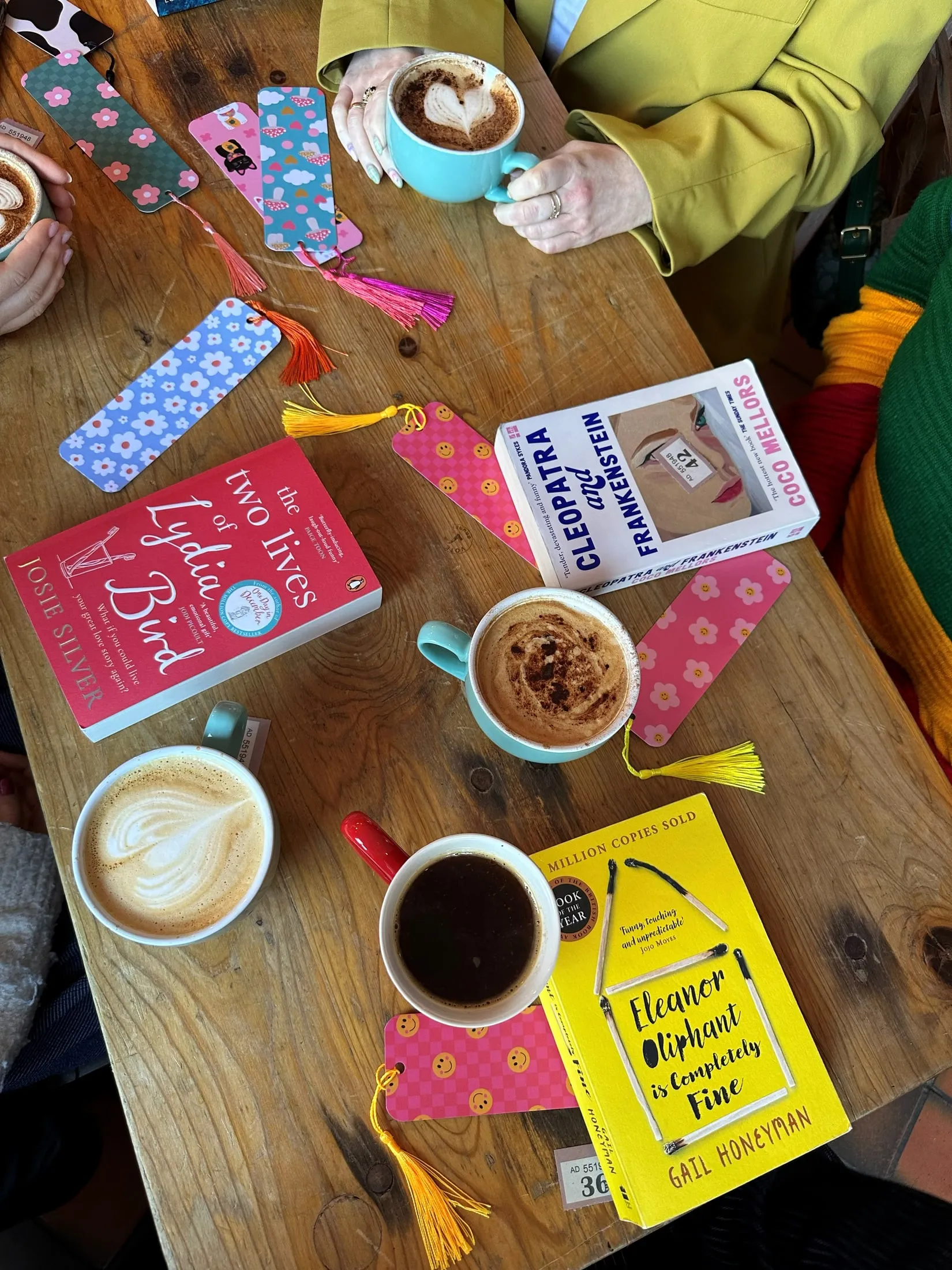 Books, coffees and bookmarks on a café table, seen from above