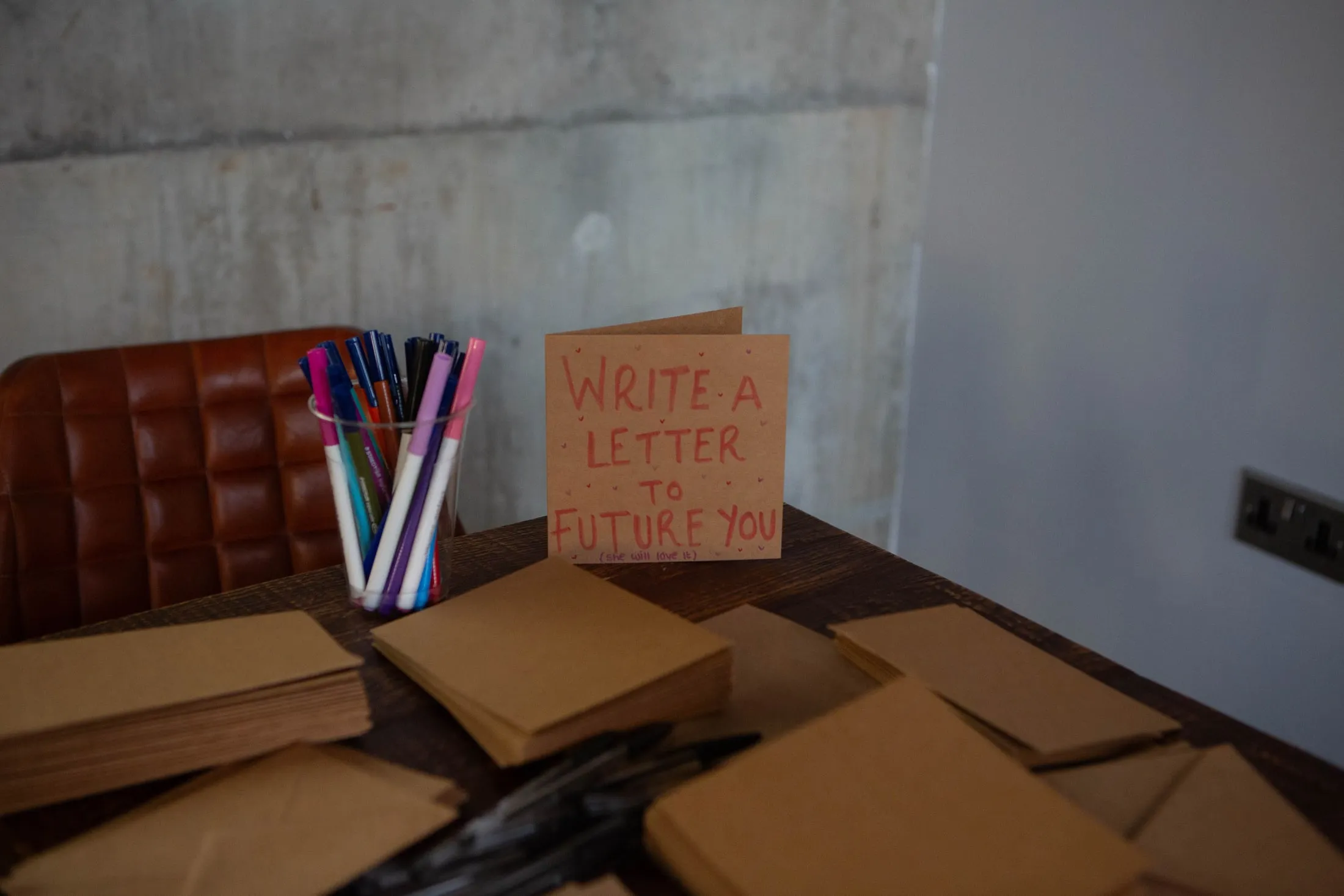 A handwritten card saying ‘Write a letter to future you’ beside brown envelopes and felt-tip pens