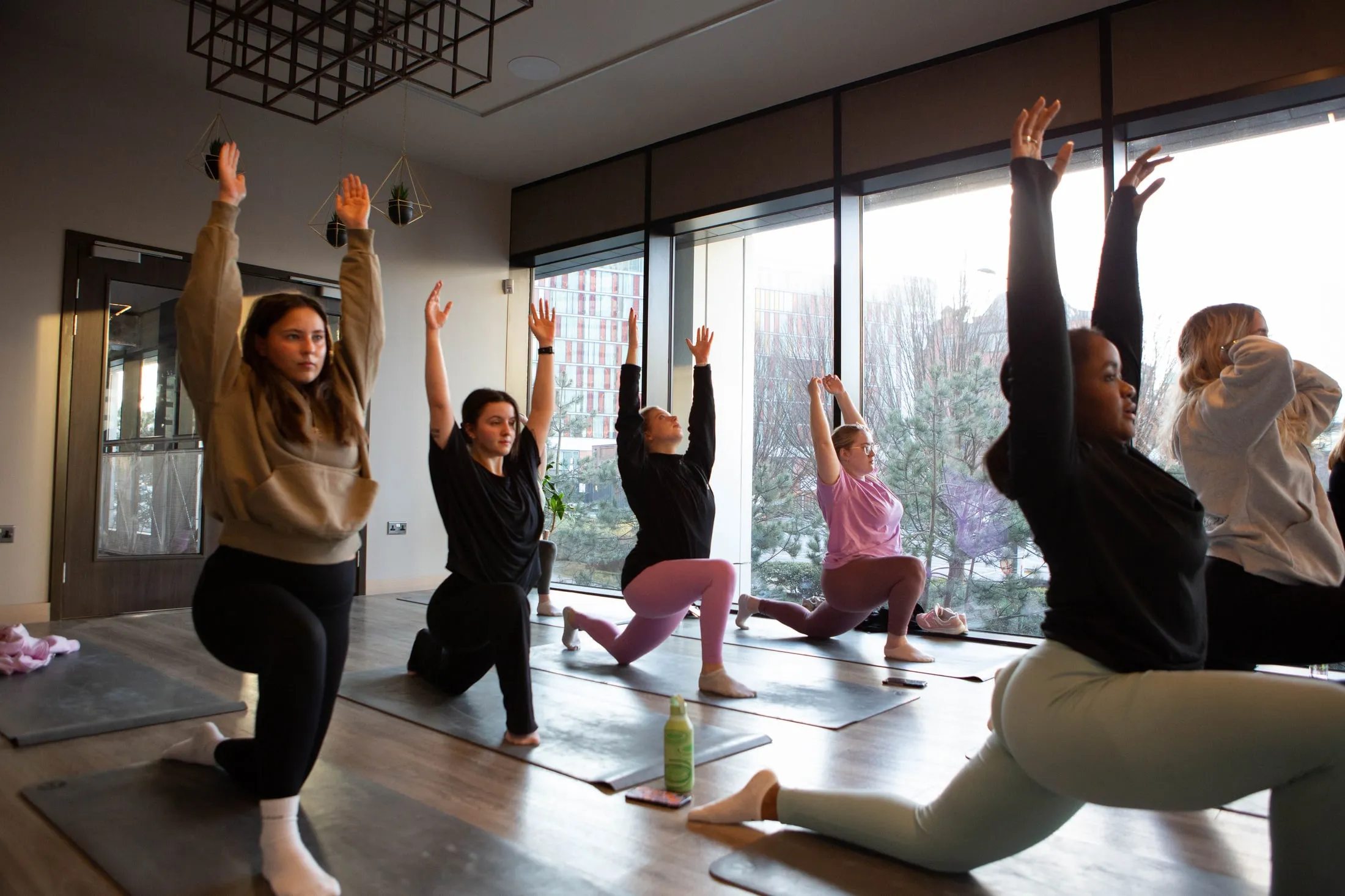 Women stretching in a fitness studio with big windows