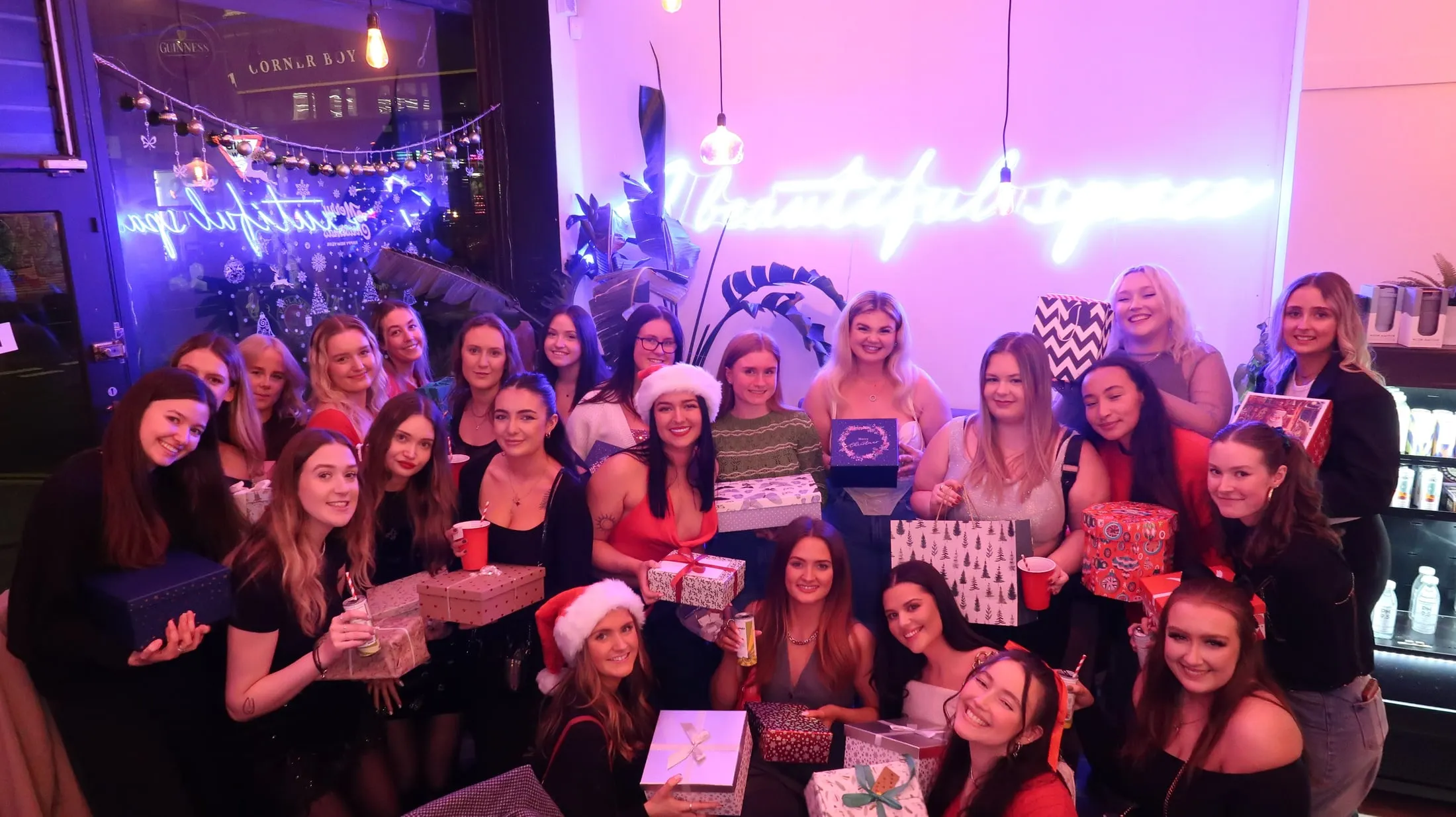A Christmas party group in Santa hats, lit pink and purple