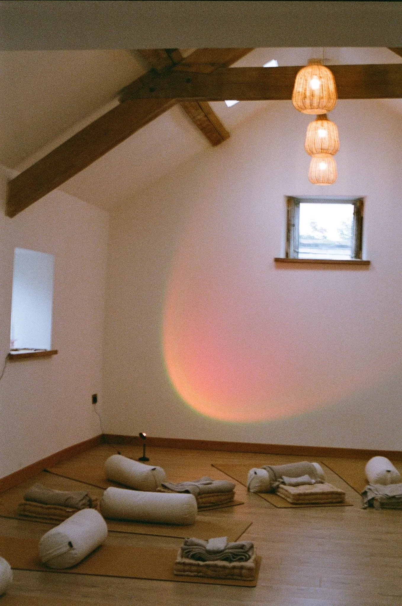 A retreat studio with floor cushions and a sunset lamp glowing pink on the wall, shot on film