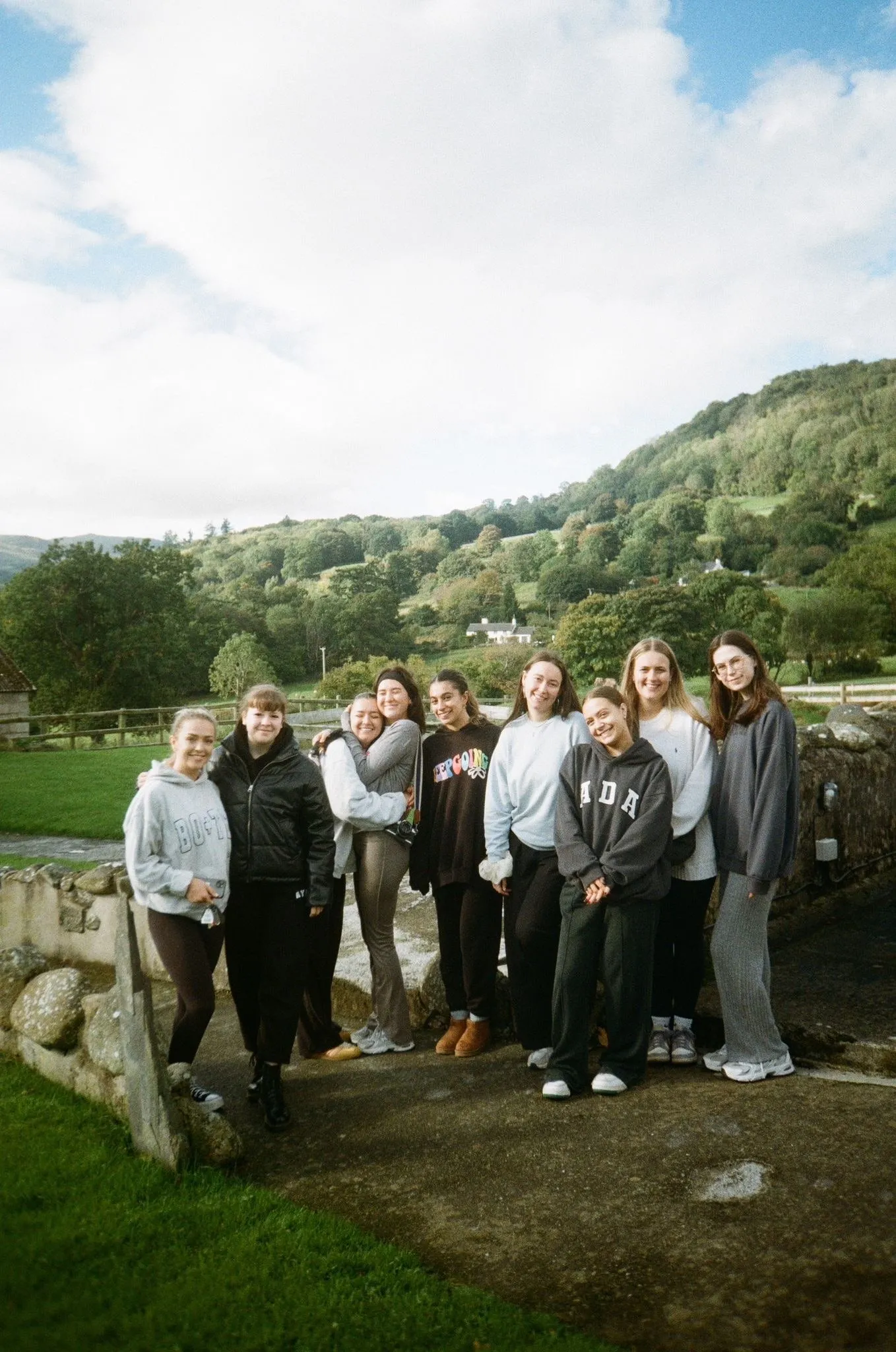 A group of women standing together by a fence in the hills, shot on film