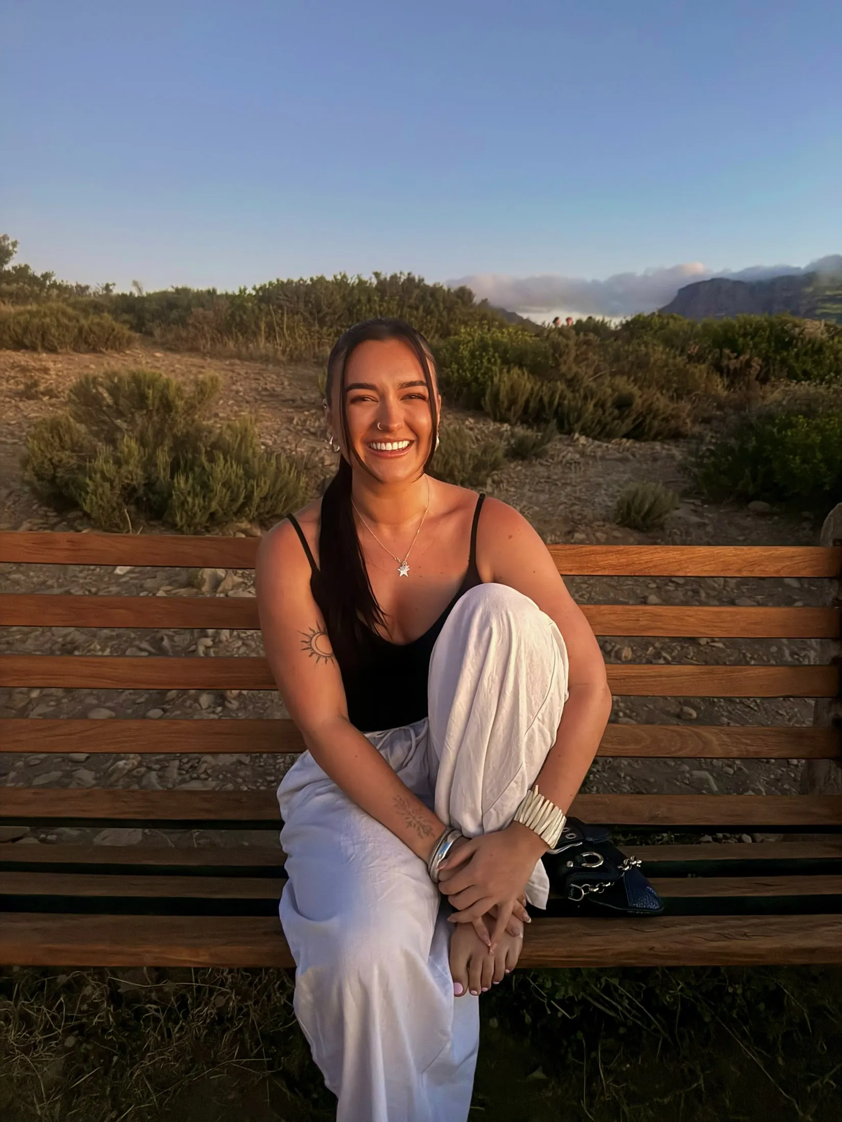 Megan smiling on a wooden bench in the evening sun