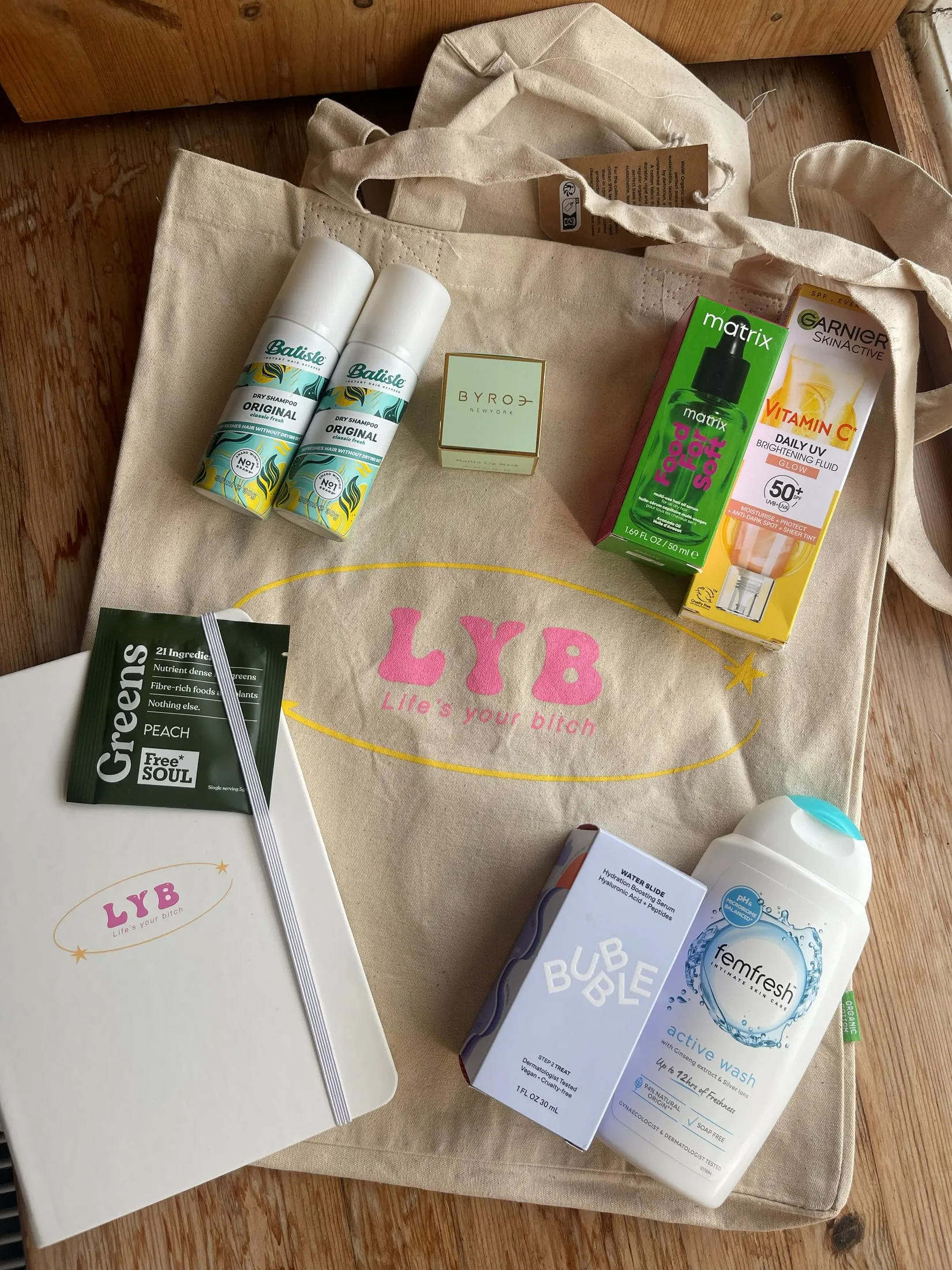 An LYB tote bag, notebook and skincare treats laid out on a table