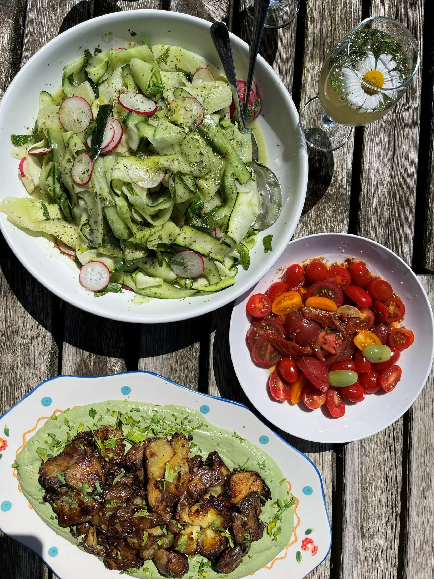 Bowls of cucumber salad, tomatoes and roasted aubergine on a wooden table
