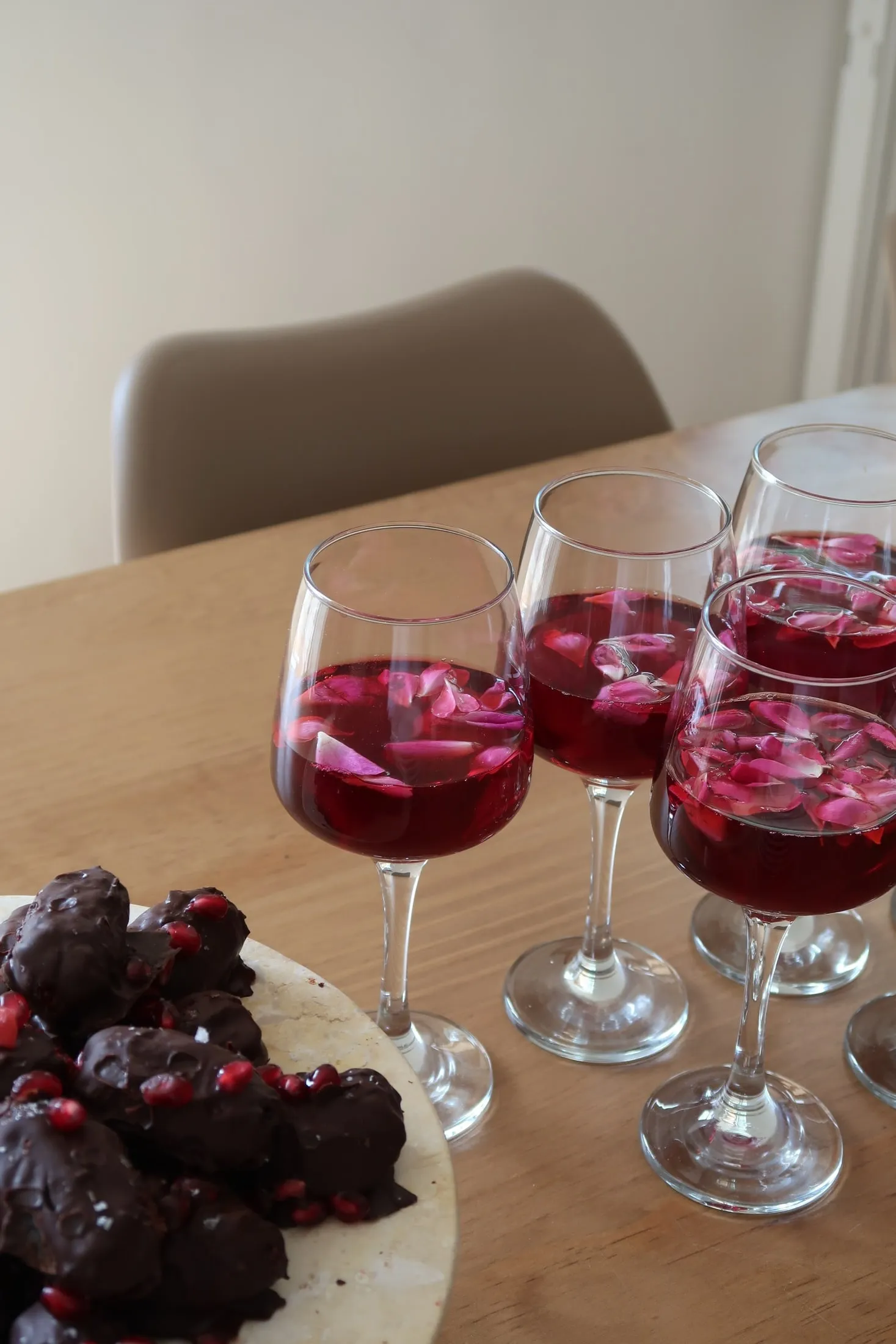 Glasses of red drinks next to chocolate treats on a table